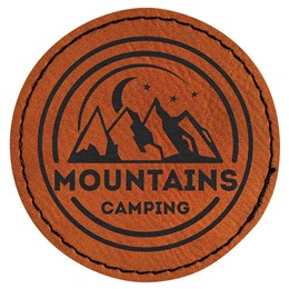 A round laserable leatherette patch that has mountains ingraved in the middle with the letters "Mountains camping" underrneath.